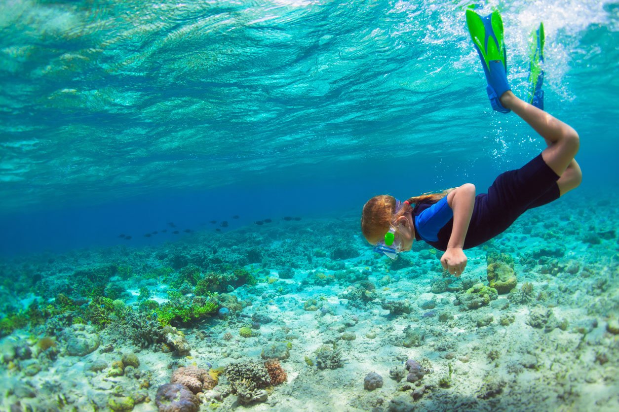 Enfant au masque de plongée plongée sous-marine dans le lagon bleu de la mer