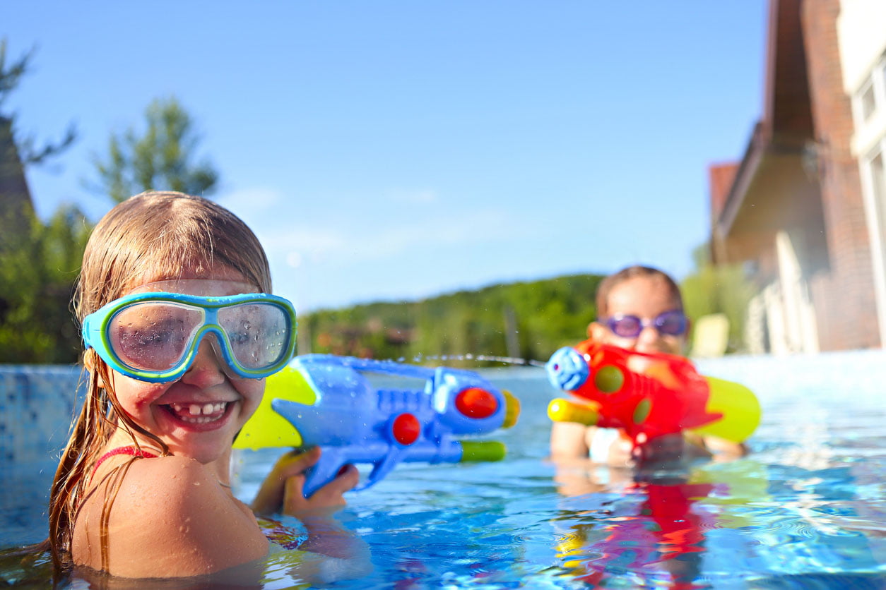 Petites filles drôles jouant avec des pistolets d'eau dans la piscine