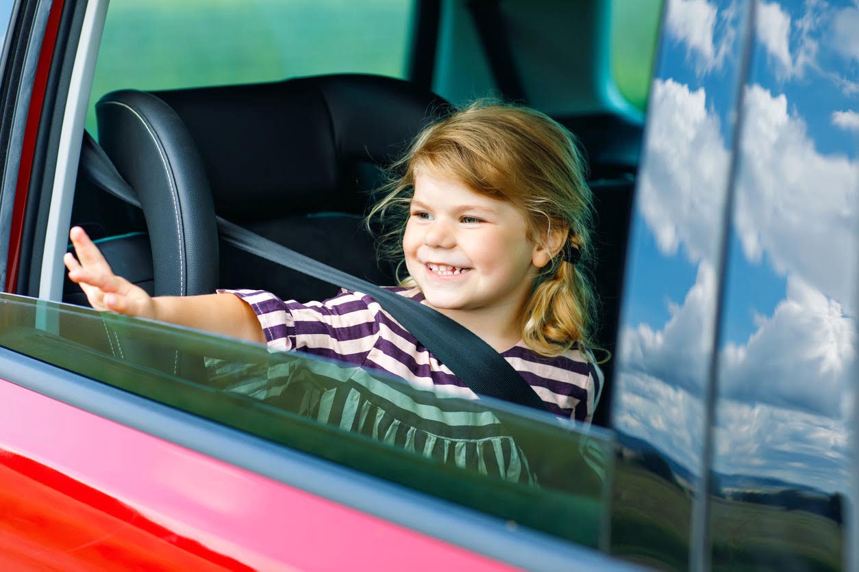 Fille adorable d’enfant en bas âge se reposant dans le siège d’auto et regardant par la fenêtre sur la nature et la circulation