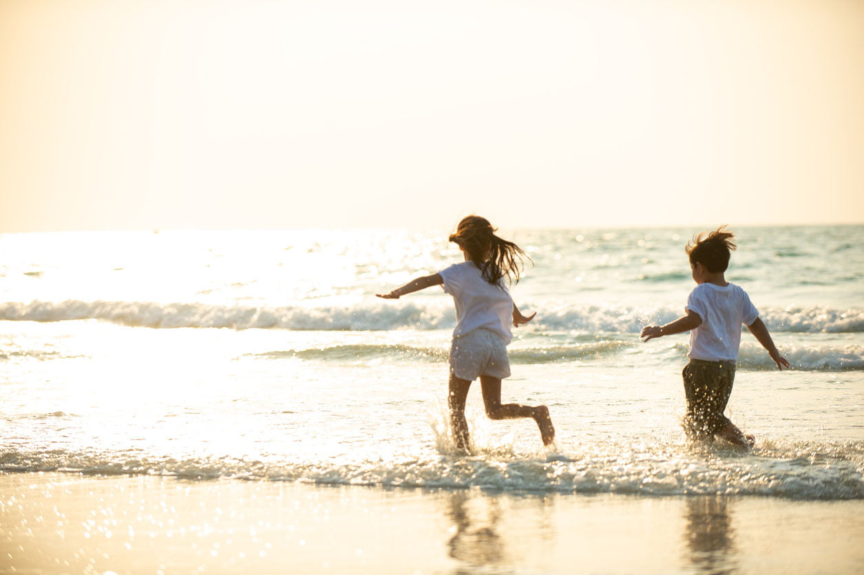 Petit garçon asiatique et frère de fille jouant ensemble sur la plage sur des vacances d’été