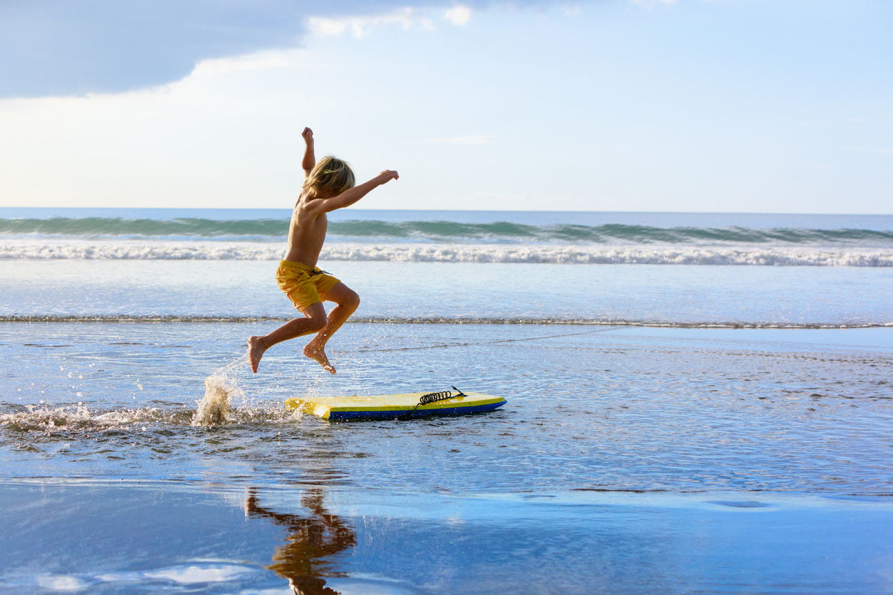 Garçon avec bodyboard amusez-vous sur la plage de la mer