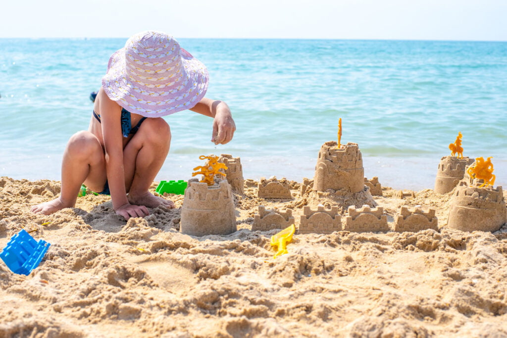 Un enfant est en train de construire un château de sable sur la mer