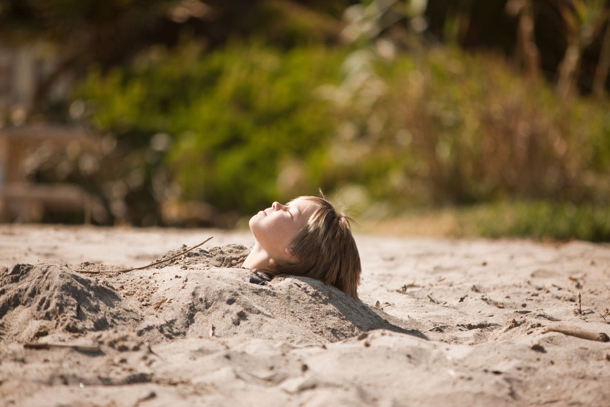 Garçon ensevelies jusqu'à son cou dans le sable