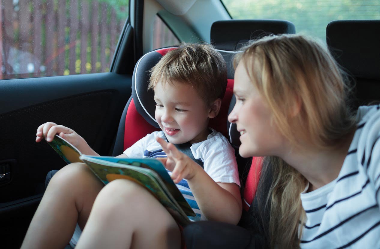Mère et fils avec un livre dans la voiture
