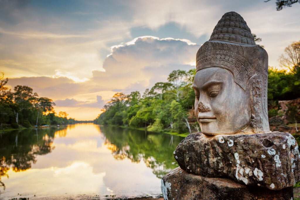Face en pierre Asura et coucher de soleil sur douves. Angkor Thom, Cambodge
