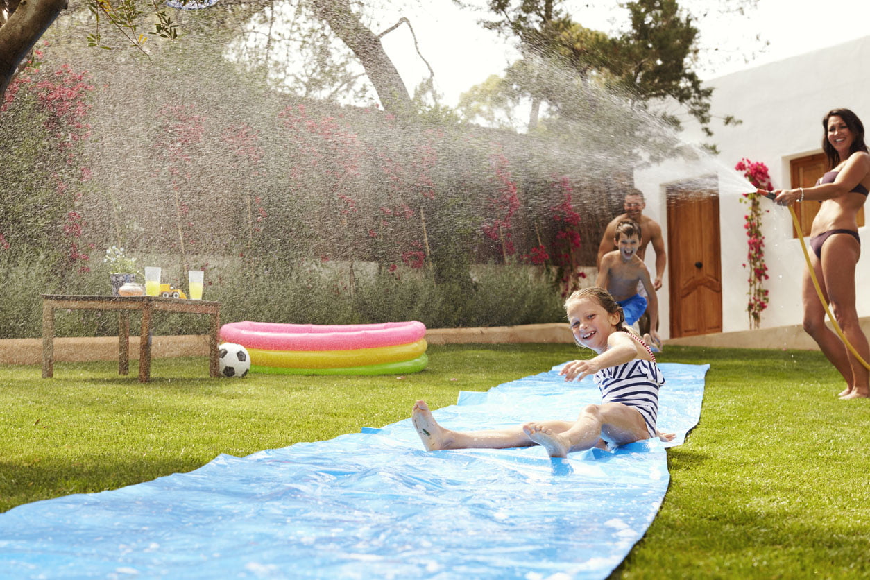 La famille s’amuse sur le toboggan aquatique dans le jardin