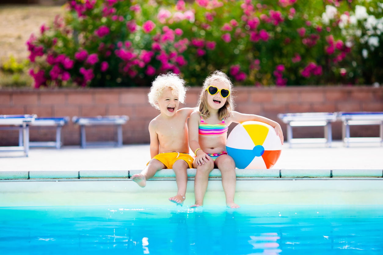 Enfants jouant au bord de la piscine en plein air avec une balle