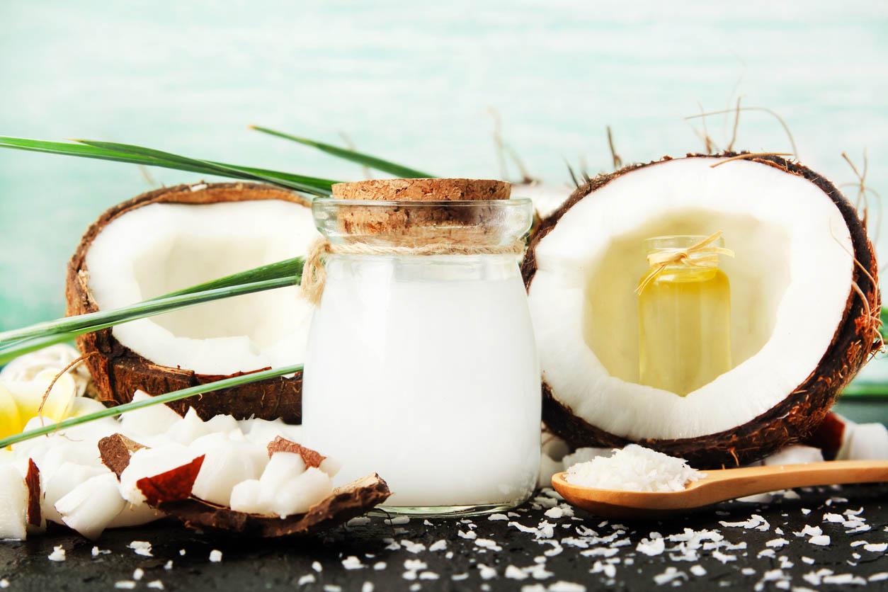 Pot de verre de lait de coco avec les noix et les bouteilles d’huile, flocons de noix de coco fraîche