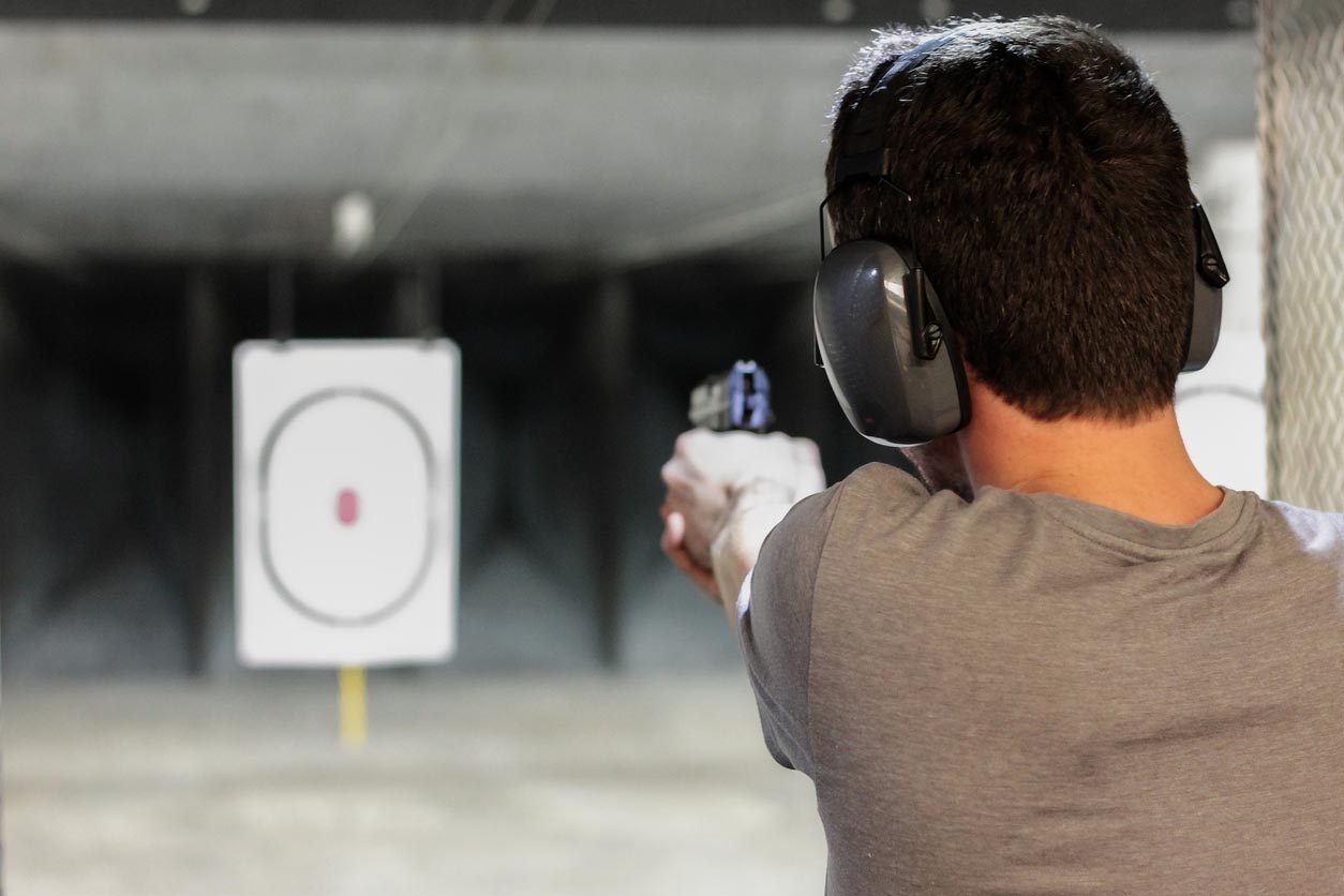 Un homme tire avec une arme à feu dans un stand de tire