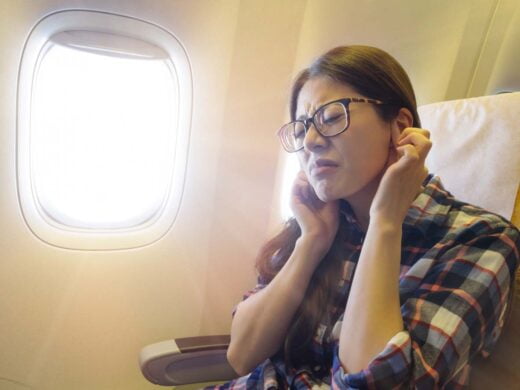 femme dans l'avion se bouche les oreilles