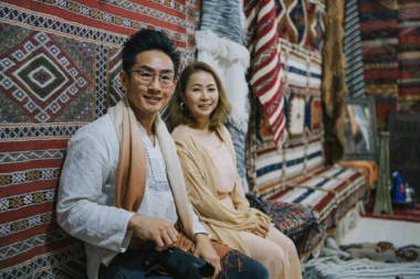 Un touriste chinois asiatique assis dans un magasin de tapis regardant la caméra souriant à Tinghir, au Maroc