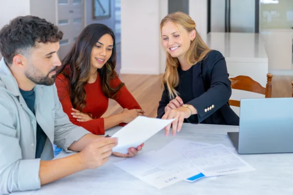 Agent immobilier avec un couple examinant des documents en vue d'une visite immobilière