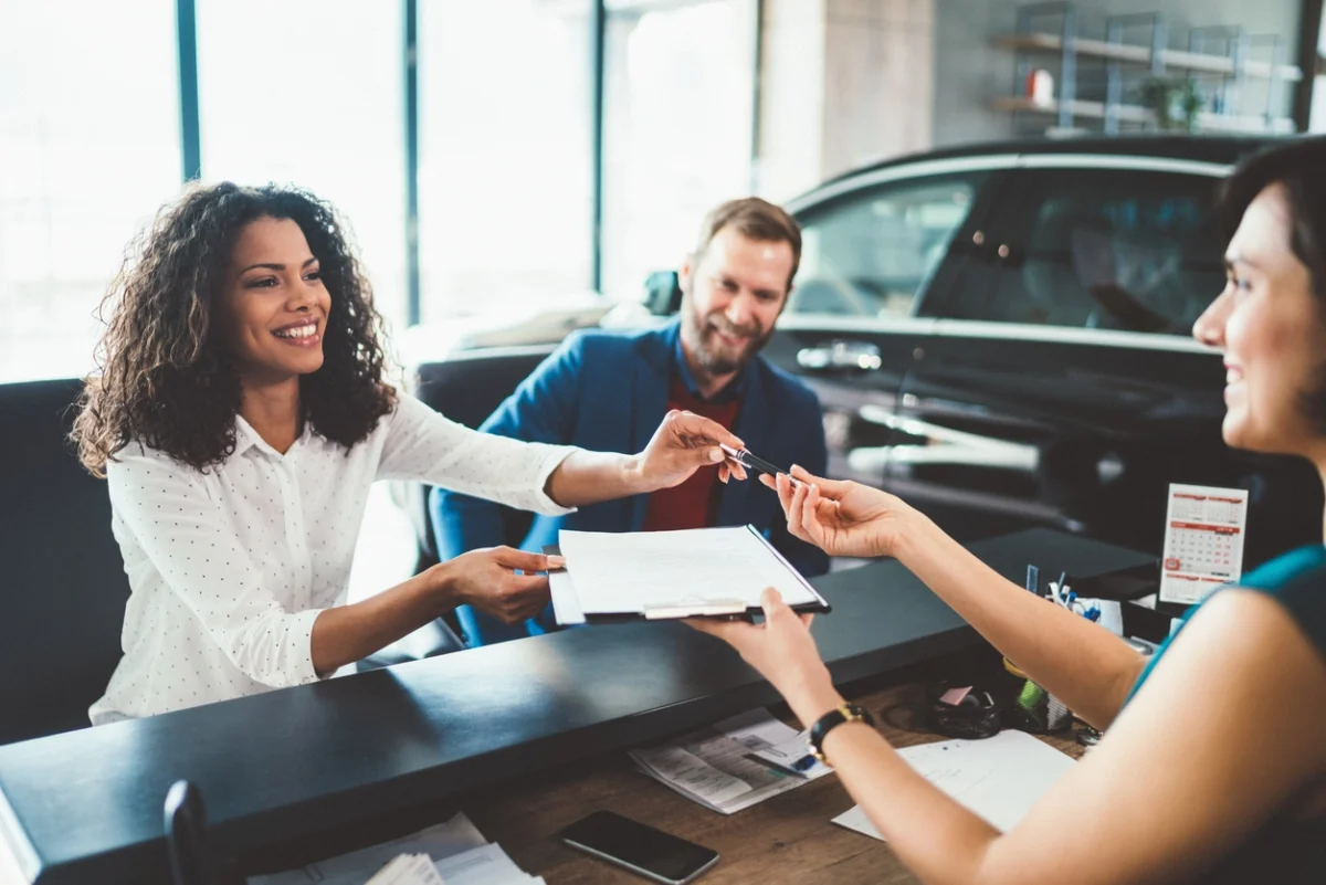 Un couple louant une voiture après avoir effectué toutes les vérifications nécessaires et signé le contrat